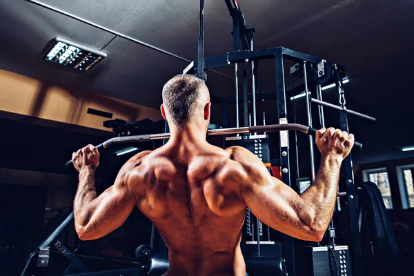 Arka üstünde makine için ağır egzersiz yaparak güçlü vücut geliştirmeci — Stok fotoğraf