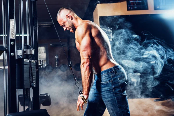 Guapo musculoso fitness culturista haciendo ejercicio de peso pesado para tríceps en el gimnasio — Foto de Stock