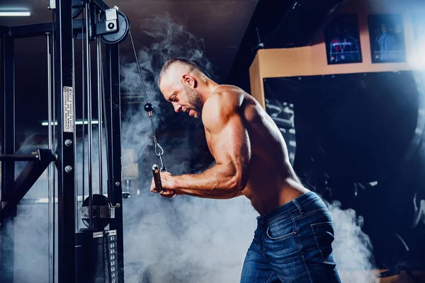 Красавчик мускулистый бодибилдер, занимающийся тяжелой физической нагрузкой для трицепсов в тренажерном зале — стоковое фото