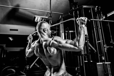 Arka üstünde makine için ağır egzersiz yaparak güçlü vücut geliştirmeci
