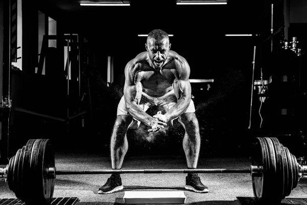 Der muskulöse Gewichtheber klatscht in die Hände und bereitet sich auf das Training im Fitnessstudio vor. Schrei nach Motivation — Stockfoto