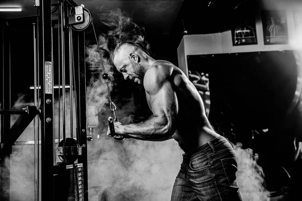 Guapo musculoso fitness culturista haciendo ejercicio de peso pesado para tríceps en el gimnasio — Foto de Stock