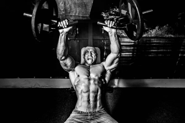The athlete doing exercises on pectoral muscles in smoke. GYM — Stock Photo, Image