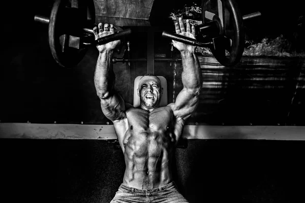 The athlete doing exercises on pectoral muscles in smoke. GYM — Stock Photo, Image