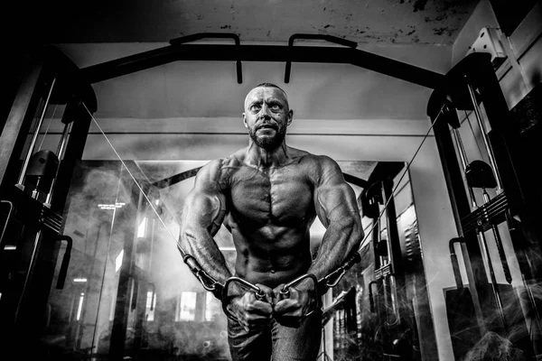 Bodybuilder Is Working On His Chest With Cable Crossover In Gym. Smoke on background — Stock Photo, Image