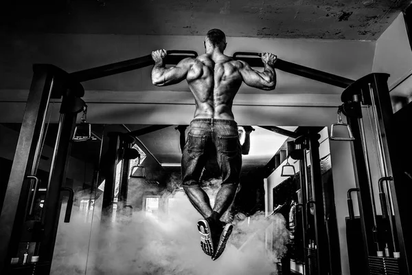 Jovem atleta exercitando-se em bares no ginásio — Fotografia de Stock