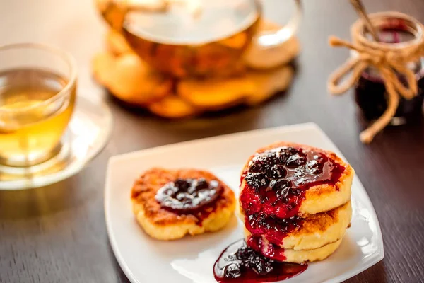 Süßkäsepfannkuchen auf einem weißen Teller mit grünem Kamillentee. Selektiver Fokus. geringe Schärfentiefe. — Stockfoto