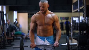 Spor salonunda büyük dumbbell ile pazı egzersizleri yaparken kas vücut geliştirmeci adam