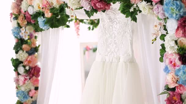 Attractive young woman coming at the bed canopy decorated with flowers, Touches a wedding dress, admires it and looking at camera. — Stock Video