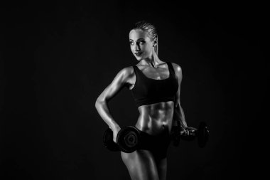 At kuyruğu siyah arka plan üzerine dumbbells ile poz bikini ile cinsel kaslı sarışın yan görünüm.