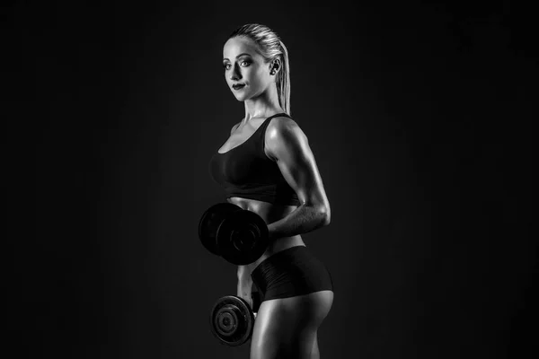 At kuyruğu siyah arka plan üzerine dumbbells ile poz bikini ile cinsel kaslı sarışın yan görünüm. — Stok fotoğraf