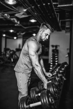 Yakışıklı kaslı adam egzersiz ve spor salonunda dumbbells ile poz