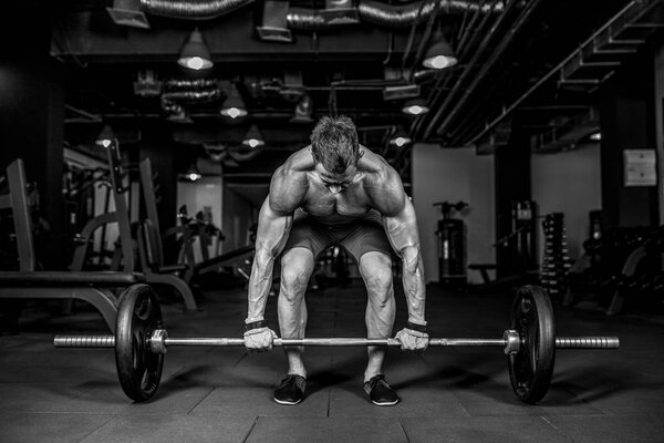 Young shirtless man doing deadlift exercise at gym. motivation.