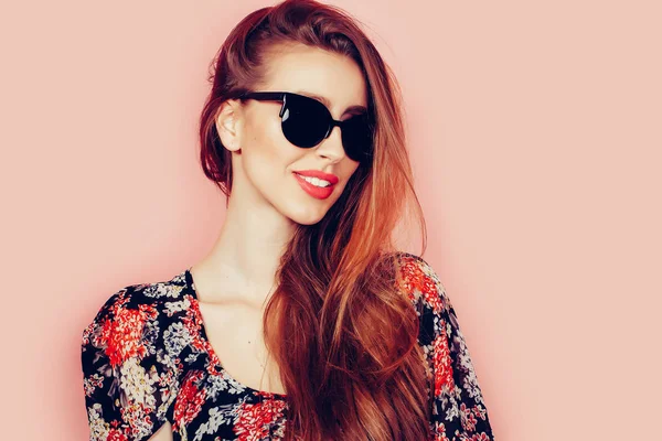Retrato de joven hermosa mujer delgada en vestido sexy con labios sensuales en el estudio con gafas de sol sonriendo y posando — Foto de Stock