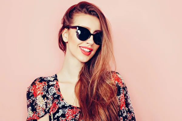 Retrato de joven hermosa mujer delgada en vestido sexy con labios sensuales en el estudio con gafas de sol sonriendo y posando — Foto de Stock
