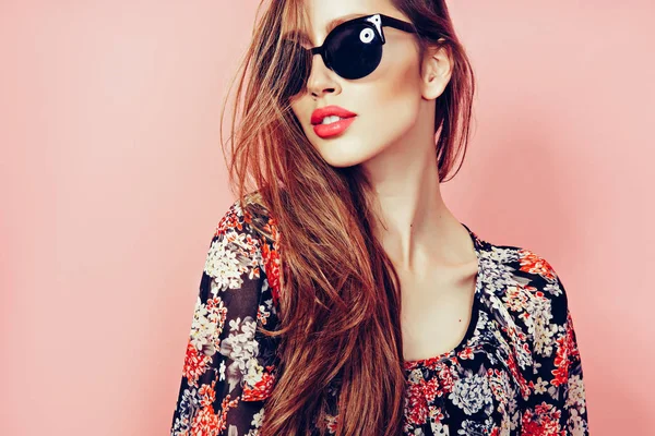 Portrait of young beautiful slim woman in sexy dress with sensual lips in studio wearing sunglasses smiling and posing — Stock Photo, Image
