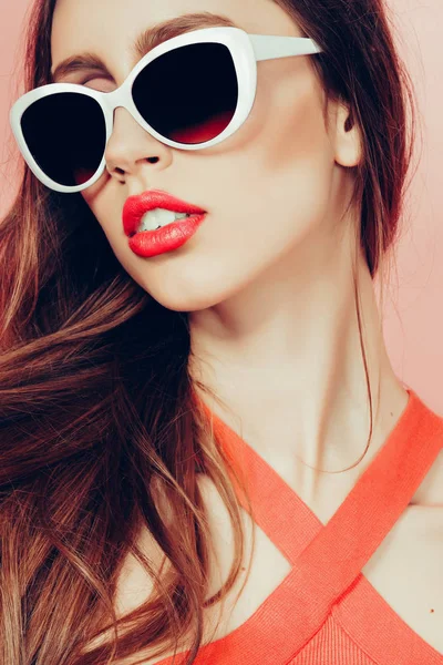 Портрет молодої красивої стрункої жінки в сексуальній сукні з чуттєвими губами в студії в сонцезахисних окулярах посміхається і позує — стокове фото