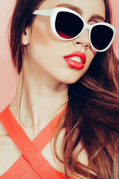 Портрет молодої красивої стрункої жінки в сексуальній сукні з чуттєвими губами в студії в сонцезахисних окулярах посміхається і позує — стокове фото