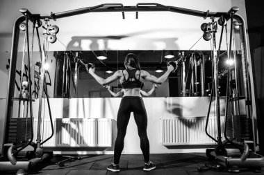 kablo makine içinde jimnastik salonu kas esneme kadın. pazı üzerinde egzersiz. Arkadan Görünüm