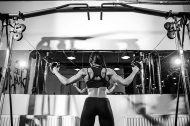 kablo makine içinde jimnastik salonu kas esneme kadın. pazı üzerinde egzersiz. Arkadan Görünüm