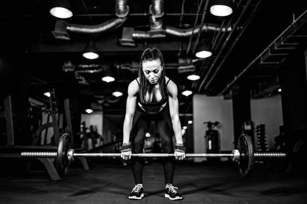 Muscular joven fitness mujer haciendo ejercicio de levantamiento de pesas pesado en el gimnasio — Foto de Stock