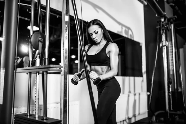 Woman flexing muscles on cable machine in gym. exercise on triceps — Stock Photo, Image