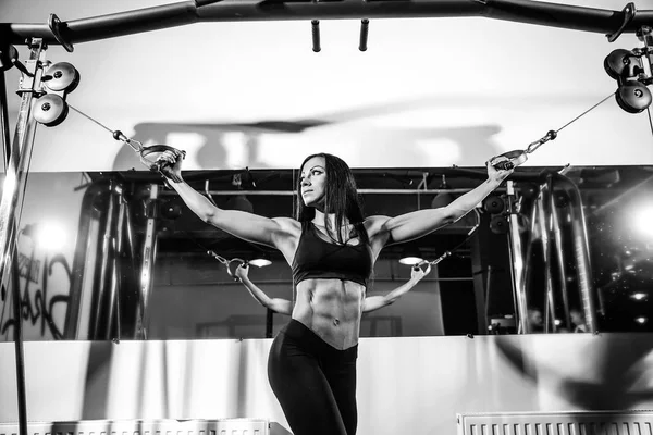 woman flexing muscles on cable machine in gym. exercise on biceps