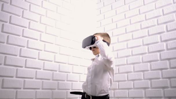 Маленький хлопчик використовує пристрій віртуальної реальності в студії — стокове відео