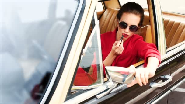 Schöne Frau mit schwarzer Sonnenbrille sitzt im Retro-Auto und macht Make-up — Stockvideo