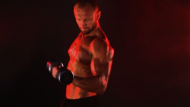 強力なスポーツマンは煙の中で重いダンベルを持ち上げる — ストック動画
