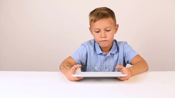Jovem menino loiro bonito em camisa azul usando tablet — Vídeo de Stock