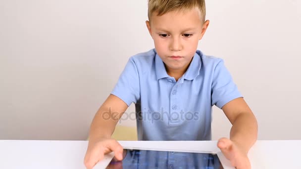 Jovem menino loiro bonito em camisa azul usando tablet — Vídeo de Stock