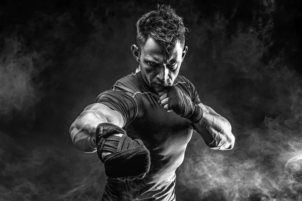 Muscular man punching in smoke. Studio — Stock Photo, Image