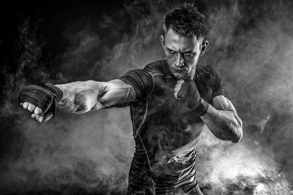 Muscular man punching in smoke. Studio — Stock Photo, Image