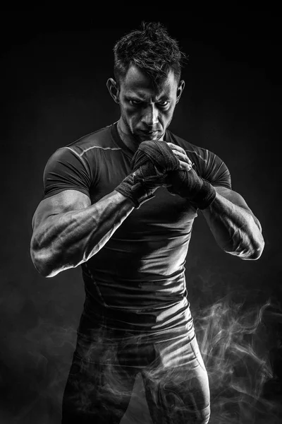 М'язистий чоловік готується до удару в дим. студії — стокове фото