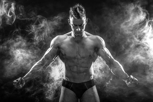 Stilig power atletisk man bodybuilder. Konditionen muskulös kropp på mörk rök bakgrund. Perfekta hane. Awesome bodybuilder, poserar. — Stockfoto