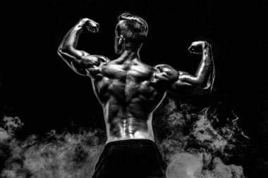 Arkadan görünüşü tanınmayan adam, güçlü kas kol ile duman içinde poz.