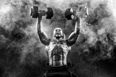 Kel üstsüz kaslı adam Bench Press duman üzerinde iki Dumbbells ile yapıyor