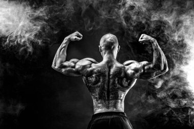 Arkadan tattoed vücut geliştirmeci uzanmış kollarıyla görünüşü