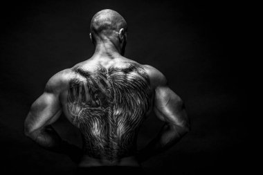 Arkadan tattoed vücut geliştirmeci uzanmış kollarıyla görünüşü