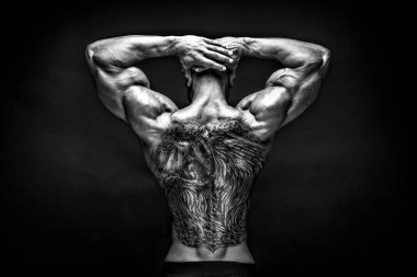Arkadan tattoed vücut geliştirmeci uzanmış kollarıyla görünüşü