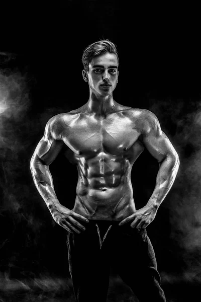 Strong bodybuilder man with perfect abs, shoulders, biceps, triceps, chest posing in smoke. — Stock Photo, Image