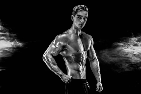 Człowiek silny kulturysta z doskonałe abs, barki, biceps, triceps, klatki piersiowej, pozowanie w dym. — Zdjęcie stockowe