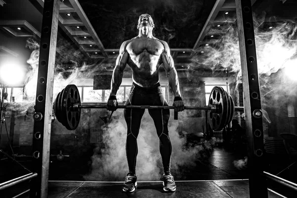 Un joven sin camisa haciendo ejercicio en el gimnasio. Gritando por motivación — Foto de Stock