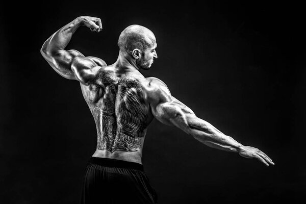 Back view of tattoed bodybuilder with outstretched arms