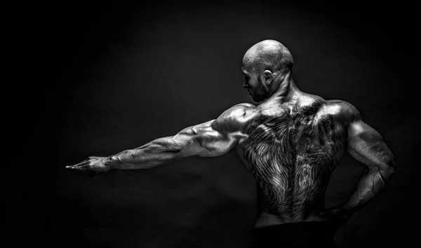 Back view of tattoed bodybuilder with outstretched arm — Stock Photo, Image