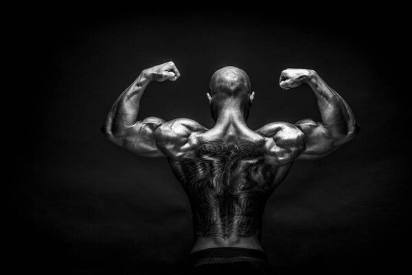 Back view of tattoed bodybuilder with outstretched arms