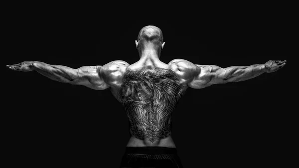 Achteraanzicht van tattoed bodybuilder met uitgestrekte armen — Stockfoto