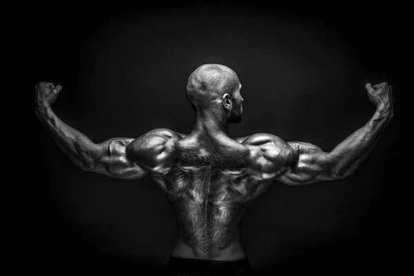 Achteraanzicht van tattoed bodybuilder met uitgestrekte armen — Stockfoto