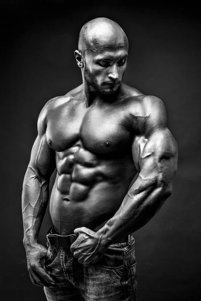 Homem de fitness musculado sem camisa. Boa aparência. Um tipo duro. Careca. Pele bronzeada. Estúdio tiro no fundo preto . — Fotografia de Stock